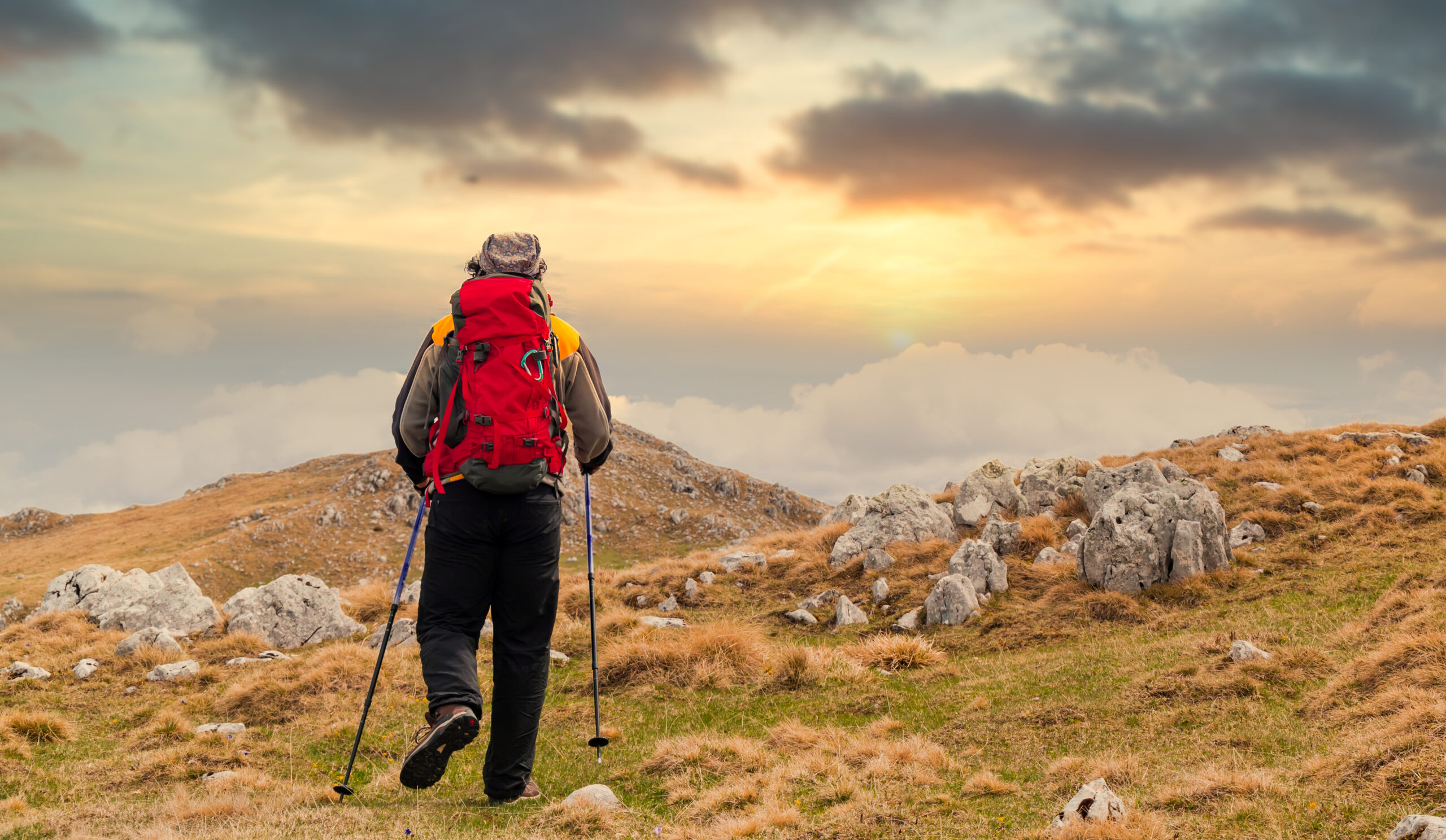 A back view of a hiker watching the sunset from a mountain